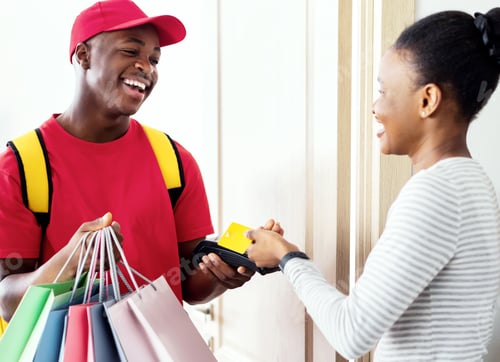 Preview: Cheerful Black Woman Paying Courier Using Credit Card At Home