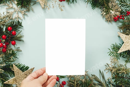 Preview: Christmas card mock up. Hand holding empty greeting card on blue background