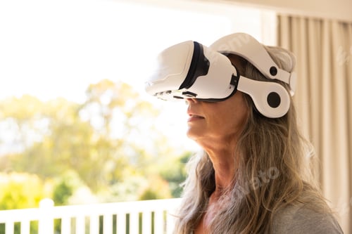 Preview: Using VR headset, mature woman exploring virtual reality at home