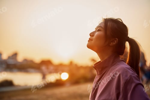 Preview: Young Asian athletic woman enjoying in sunset with her eyes closed.