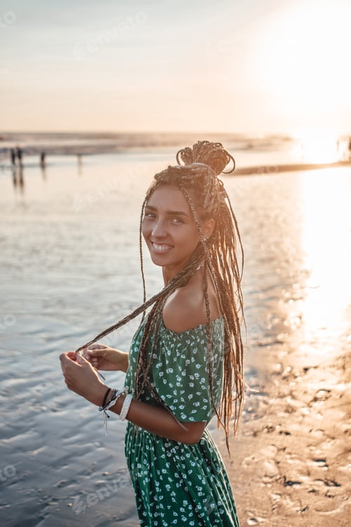 Preview: Joyful woman in dress looking at camera on beach