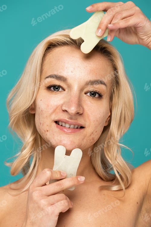 Preview: cheerful woman with blemishes using face scrapers isolated on turquoise