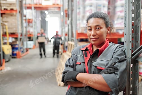 Preview: Serious young mixed-race woman in workwear and gloves crossing arms by chest