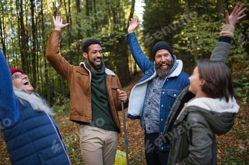 Preview: Diverse group of happy volunteers celebrating success together after cleaning up forest