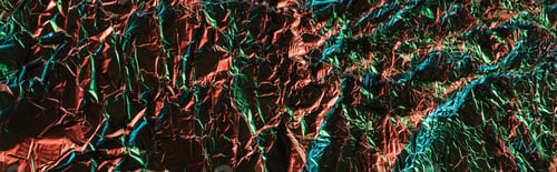 Preview: panoramic shot of glossy crumpled foil with colorful lighting reflection in darkness