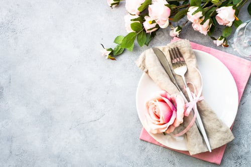 Preview: Table setting with white plate, cutlery and flowers.