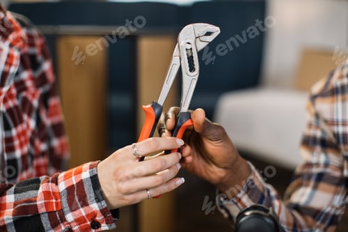 Preview: Close up of woman giving pliers to man at new home