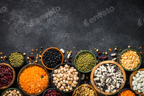 Preview: Legumes, lentils, chikpea and beans assortment on black stone table.