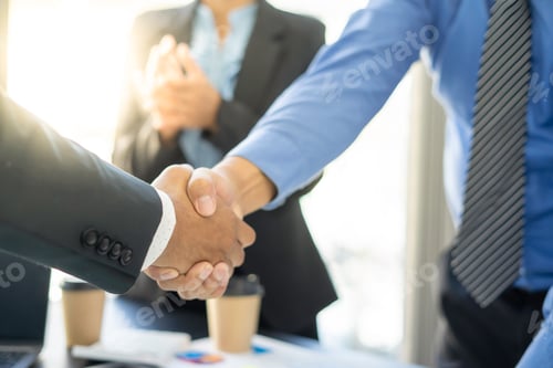 Preview: Welcome to our team! A modern young man in a smart suit shakes hands while working in a modern offic