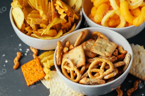 Preview: Beer snacks on stone table. Various crackers, potato chips. Top view