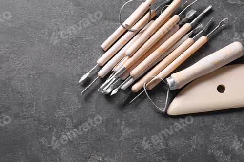 Preview: Set of different clay crafting tools on grey table, top view. Space for text