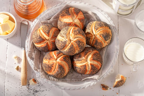 Preview: Homemade Kaiser buns with poppy seed in white basket.