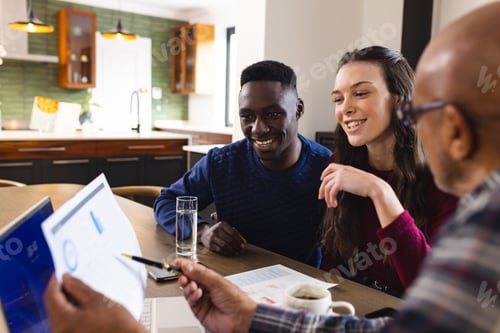 Preview: Diverse couple and biracial male financial advisor using laptop and discussing documents at home
