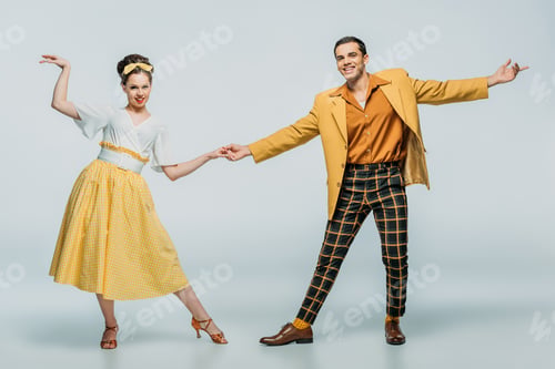 Preview: stylish dancers holding hands while dancing boogie-woogie on grey background