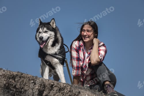 Preview: Smiling woman sitting near dog on stones