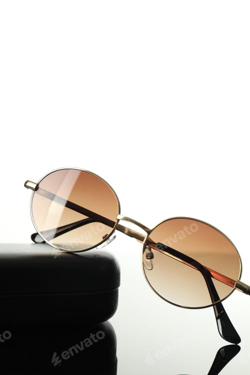 Preview: Stylish sunglasses and case on white mirror surface, closeup. Space for text