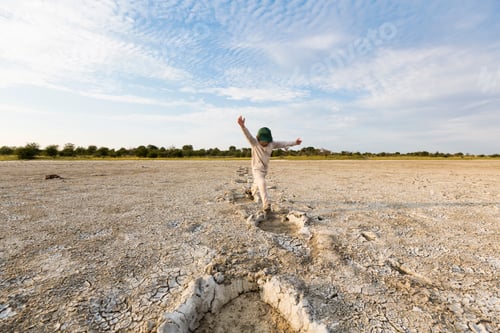 Preview: 6 year old boy leaping into elephant footprints, Nxai Pan, Botswana