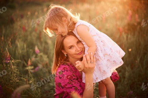 Preview: mother gently hugs her little daughter in nature