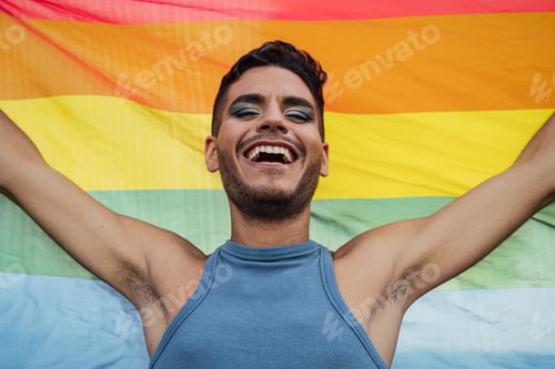 Preview: Happy homosexual man celebrating gay pride holding rainbow flag symbol of LGBTQ community