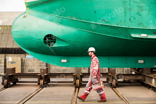 Preview: Male ship painter carrying paint cans in ship painters yard