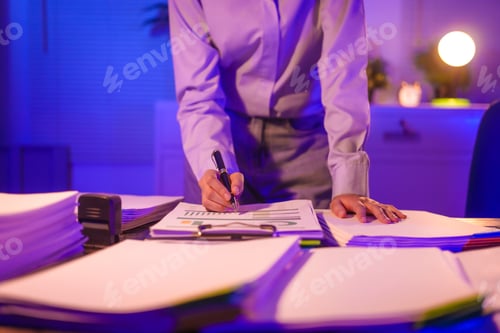 Preview: Young Asian business trainee works late at her desk, exhausted and stressed, battling deadlines.