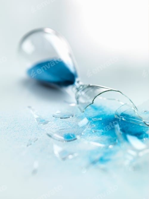 Preview: Blue sand pouring out of broken glass hourglass