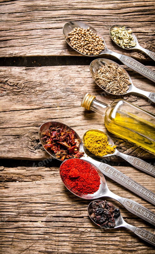 Preview: Fragrant spices in spoons with a bottle of olive oil.
