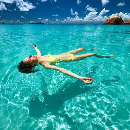 Preview: Woman In Bikini Lying On Water At Tropical Beach
