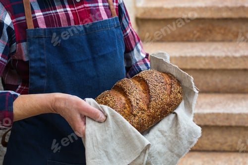 Preview: Fresh loaf of homemade rye bread in woman hands