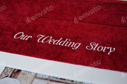 Preview: Close-up photo of an inscription saying "Our Wedding Story" on a red photobook or photo album.