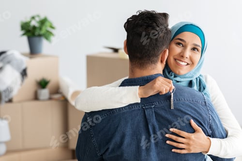 Preview: Happy muslim woman with key hugging her husband