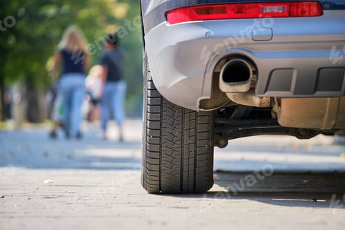 Preview: Close up of car rear wheel and exhaust pipe parked on city street side