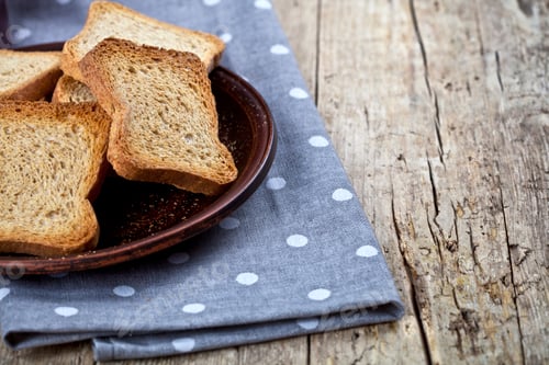 Preview: Toasted cereal bread slices on brown ceramic plate closeup on linen napkin.
