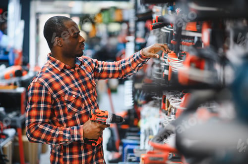 Preview: A african american man chooses a power tool in a hardware store