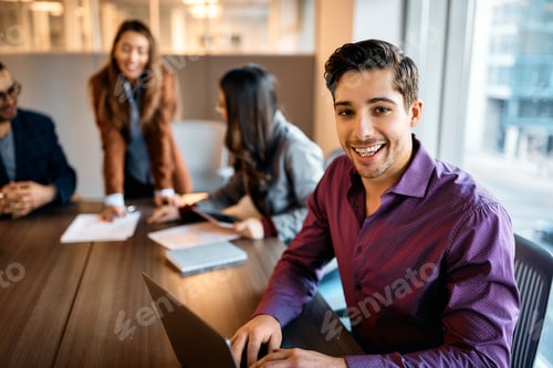 Preview: Happy entrepreneur using laptop during business meeting in the office and looking at camera.