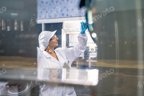 Preview: Female worker inspecting water bottle on production line in spring water factory