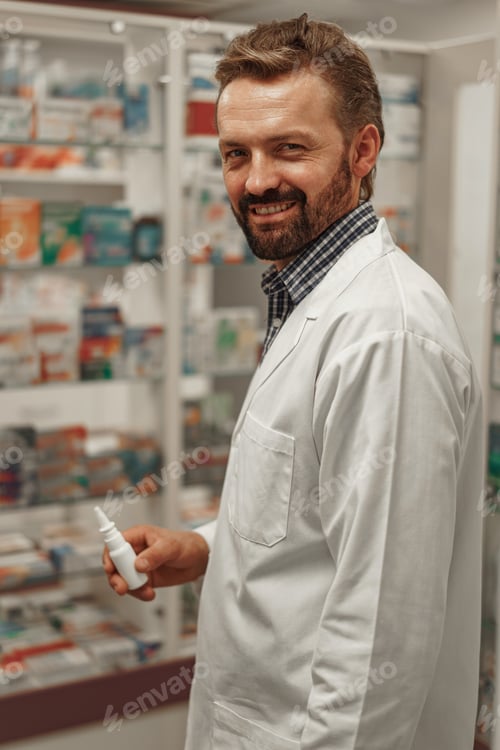 Preview: Male pharmacist and white coat holding nose spray while working at a pharmacy