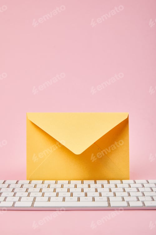 Preview: yellow envelope near computer keyboard on pink background