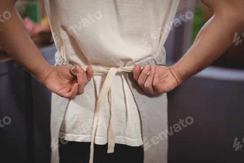 Preview: Midsection of waiter tying apron at coffee shop