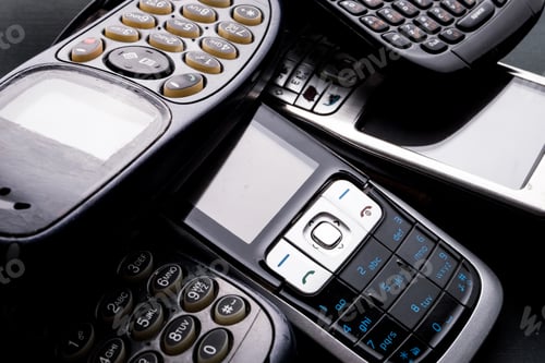 Preview: Old and obsoleted cellphones on a black background.