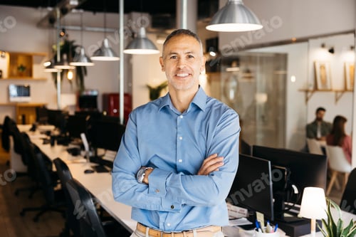 Preview: Confident mature businessman standing smiling in office