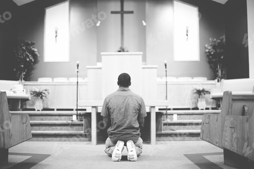 Preview: Grayscale of a male on his knees praying in the church with a blurred background