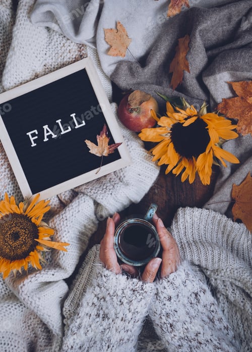 Preview: Flatlay with warm cozy sweaters, letter board with a word Fall, cup of black coffee, sunflowers