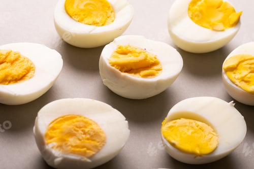 Preview: High angle close-up of fresh white boiled eggs with yellow yolks on gray table
