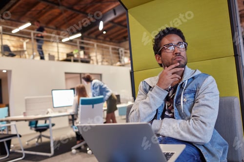 Preview: Young man working in creative start-up company, using laptop