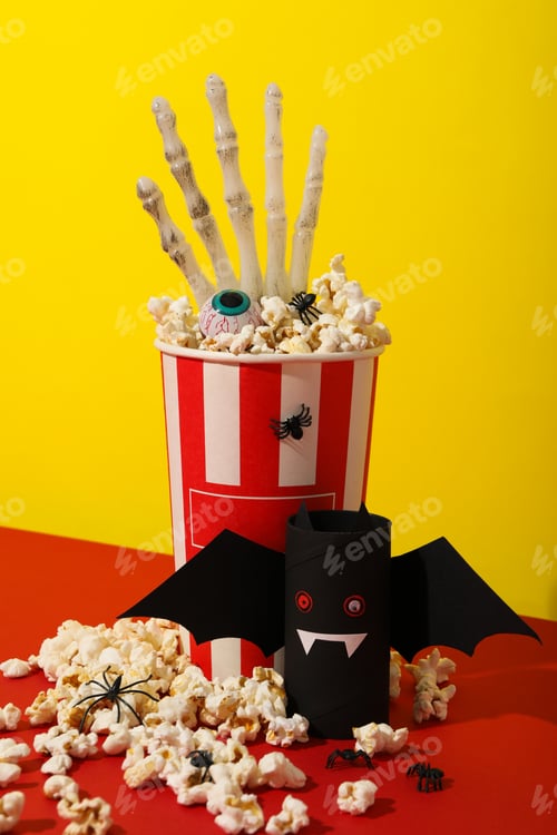 Preview: Paper cup of popcorn and Halloween decorations on yellow background
