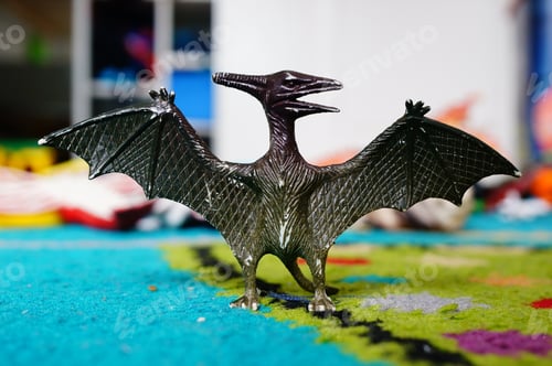 Preview: Closeup of a black toy dragon on a colorful carpet under the lights with a blurry background