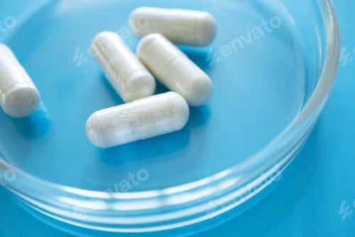 Vista previa: Probiotic supplement in capsules in glass petri dish on blue background