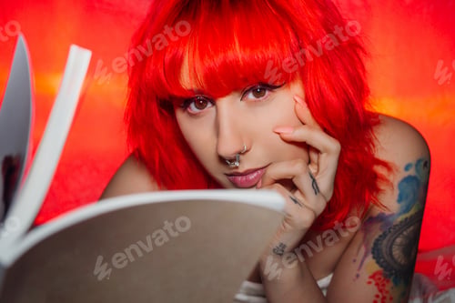 Preview: Woman with red hair and a nose piercing reading a book
