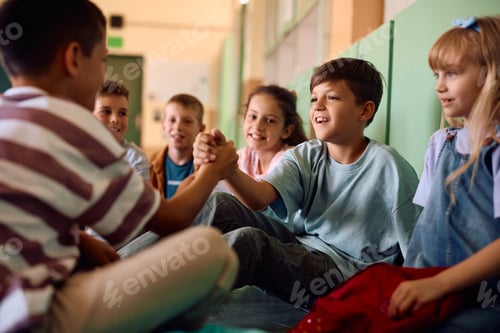 Preview: Happy boys greeting while sitting with classmates in hallway at school.